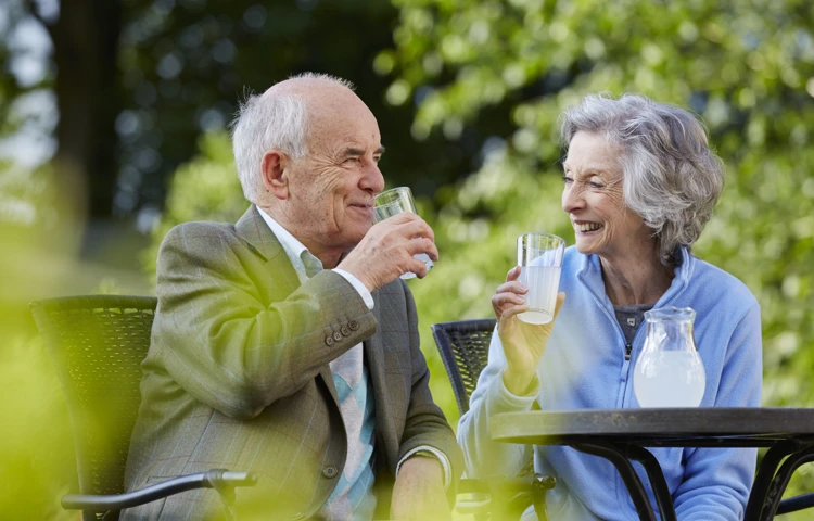 Couple enjoying a drink sitting in the sunshine at Hatch Mill