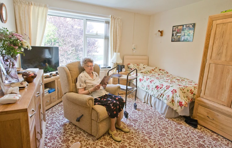 A resident is sat reading in her bedroom
