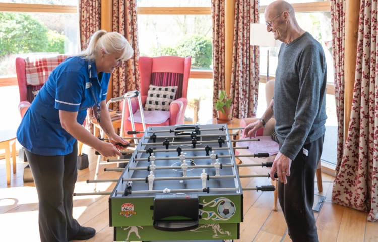 member-of-staff-and-resident-enjoying-a-game-of-table-football-together.jpg