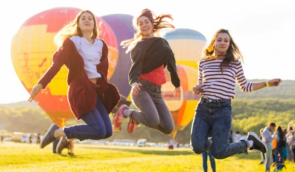 Group Of Women Jumping In Front Of Hot Air Balloons