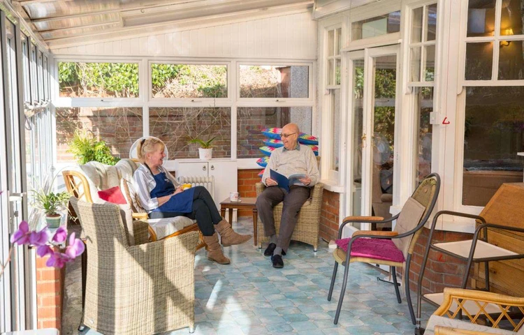 Resident and staff member at Lade House enjoying a chat in the conservatory