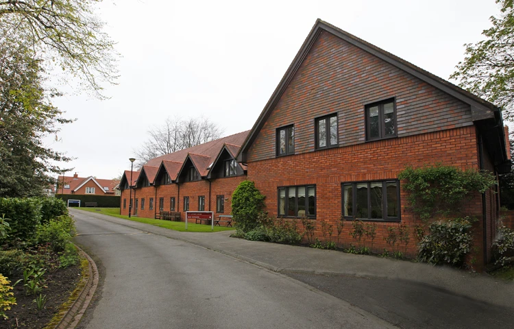 Large red brick house with trees and shrubs around it
