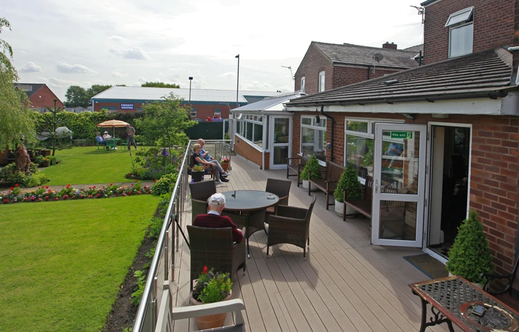 Residents are sat outside on the decked area in the sun