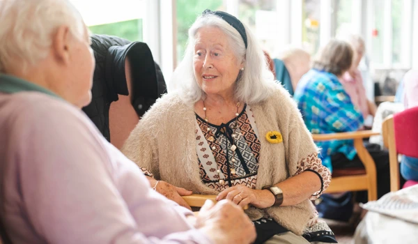 Older Man And Woman Sitting Together Chatting Indoors