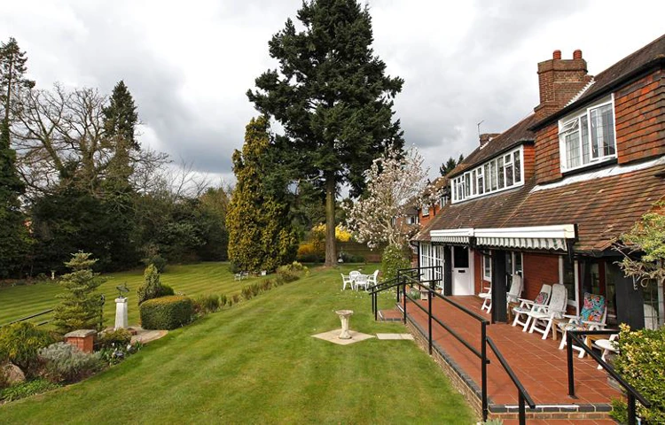 Beautifully landscaped garden with striped lawns and outdoor seating area for residents to enjoy Abbeyfield, Austenmead